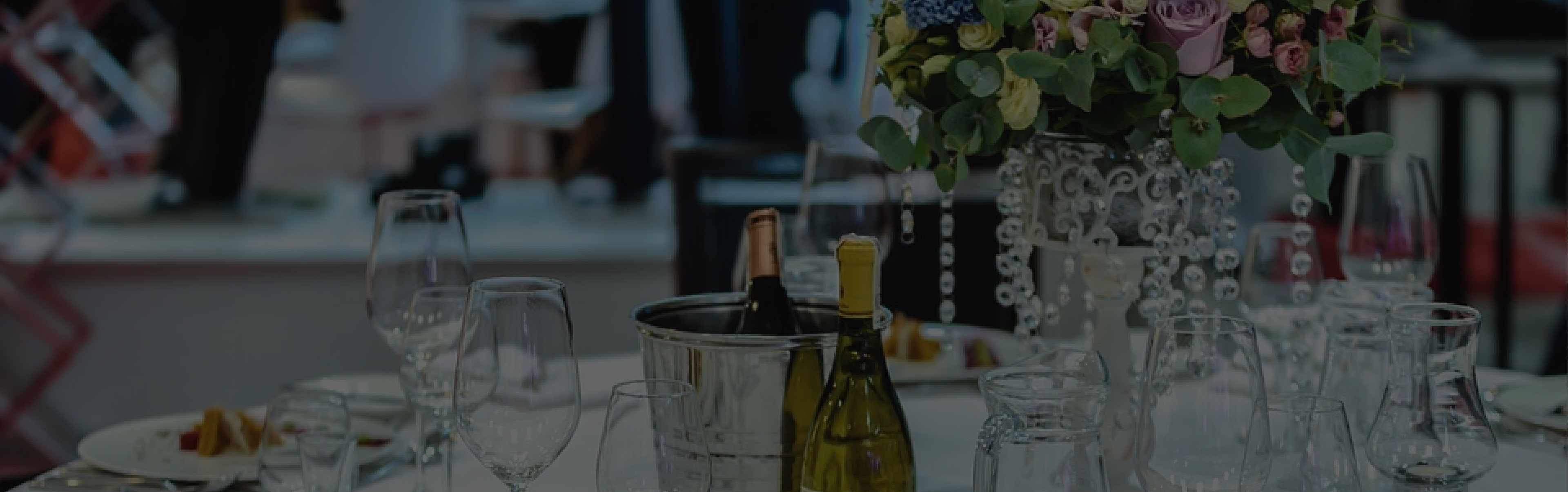Table élégamment dressée pour un événement avec des verres à vin, des bouteilles de vin et un centre de table floral, organisée par un traiteur événementiel.