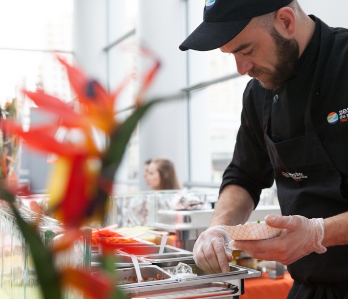 Chef traiteur en pleine préparation de plats lors d’un événement, illustrant l’attention aux détails et le savoir-faire d’un traiteur événementiel professionnel.