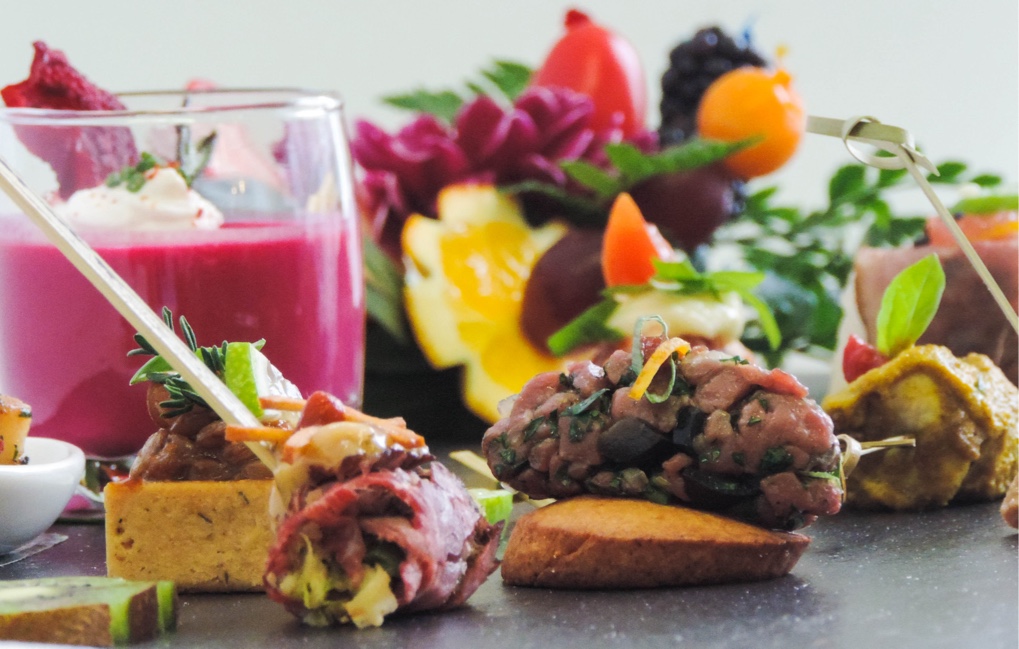 Plateau de bouchées apéritives gastronomiques et verrine colorée, mettant en valeur la créativité culinaire d’un traiteur événementiel.