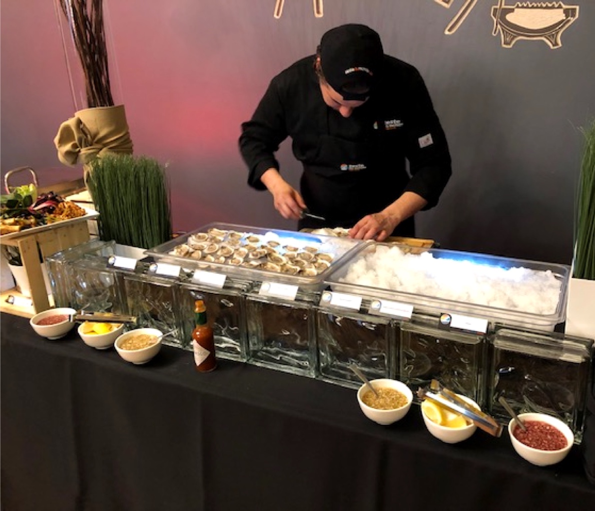Chef traiteur préparant des huîtres fraîches pour un buffet, illustrant le service personnalisé et l’attention aux détails lors d’un événement.