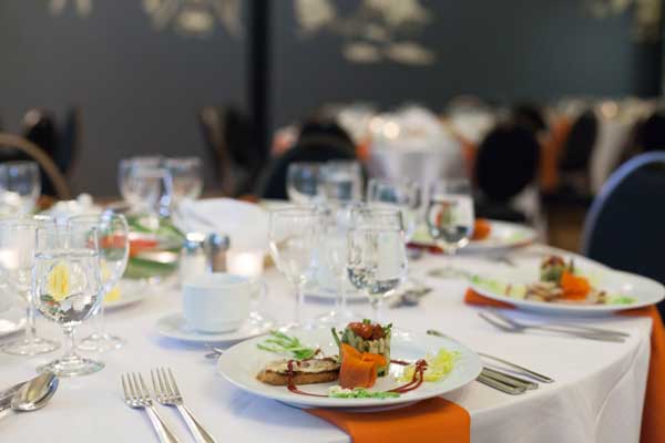 Table dressée avec assiettes gastronomiques et verrerie pour un banquet de traiteur événementiel à Montréal, créant une ambiance élégante et soignée