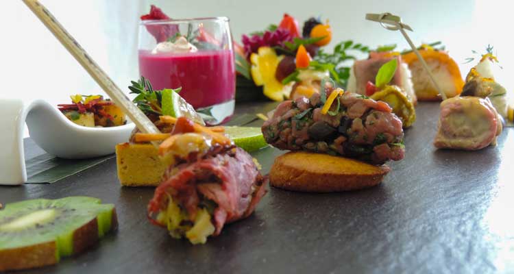 Sélection de canapés gourmets et verrine sucrée disposés sur ardoise, présentés par un traiteur événementiel pour un cocktail raffiné à Montréal