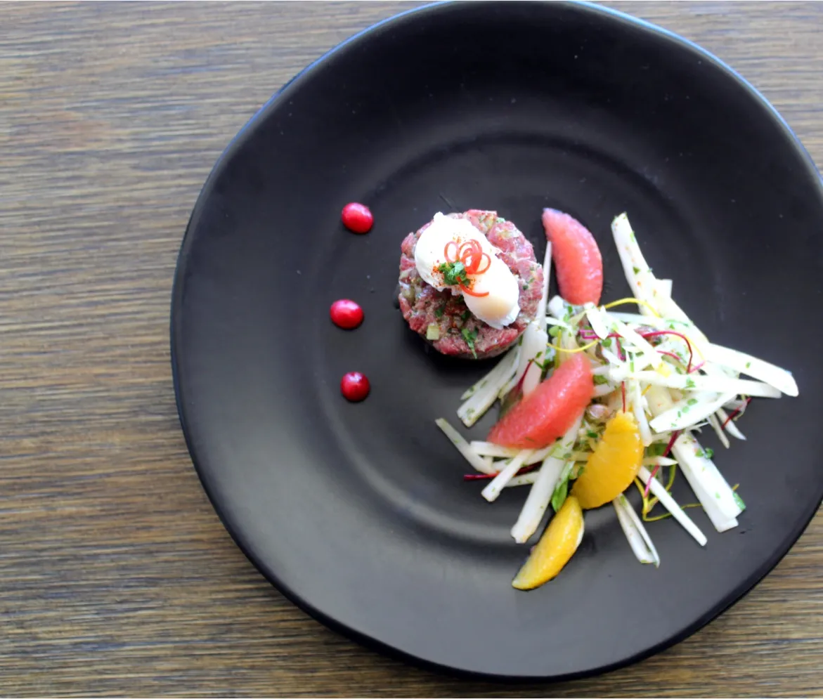 Tartare de bœuf présenté avec agrumes et salade croquante, servi dans un menu de traiteur événementiel haut de gamme pour réception à Montréal