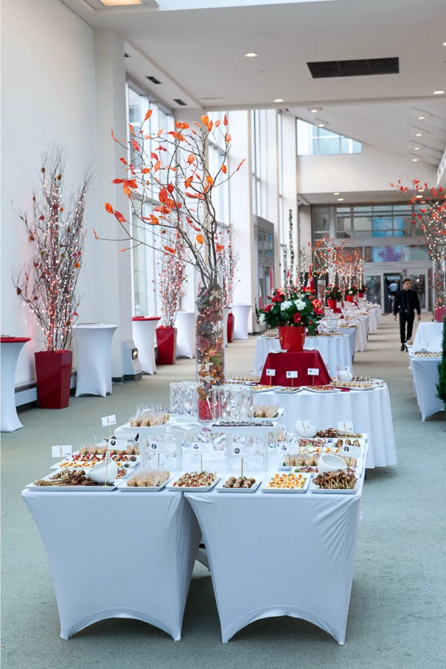 Salle de réception avec stations de bouchées et décor élégant, aménagée par un traiteur événementiel pour un grand événement corporatif à Montréal